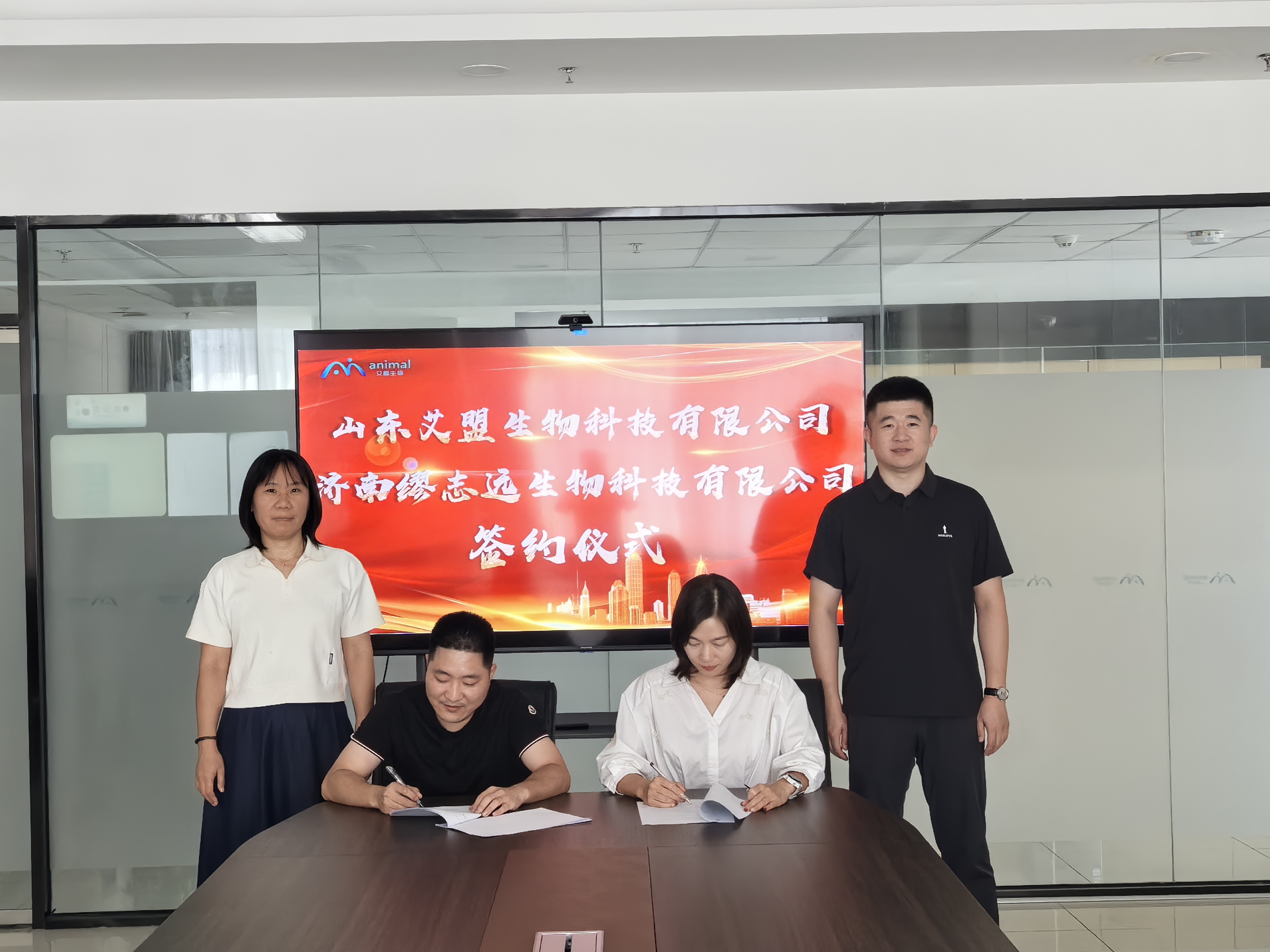 济南缪志远生物与山东艾盟生物代表在会议室签署合作协议，双方人员在场见证